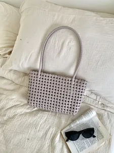 Close-up detail of the stylish lavender woven beach tote bag displayed on bed linen.