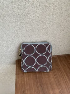 Embroidered fabric coin purse with vintage tambourine dot pattern and zipper closure detail.