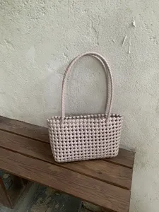 Pink woven plastic tote bag detail view, chic summer beach and casual daily handbag style.