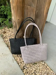 Close-up of summer woven plastic tote beach bag with hollow design and dual handles.