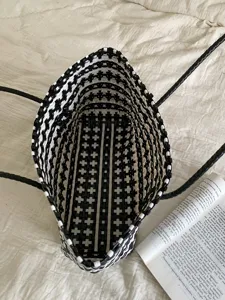 Detaillierte Ansicht von oben in das Innere einer schwarz-weißen geflochtenen Tasche.
