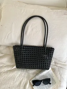 Black plastic woven tote bag, hollow beach handbag, stylish summer casual everyday commuter bag.