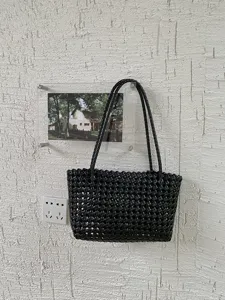 Black woven plastic tote bag detail view, perfect for summer beach vacation and daily commute use.