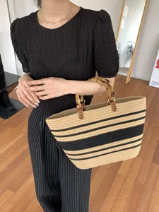 Borsa tote estiva in paglia intrecciata con eleganti manici in bambù e classico motivo a righe.
