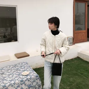 Detailansicht einer stilvollen schwarzen PU-Eimer Tasche mit gesteppter Jacke und Jeans.