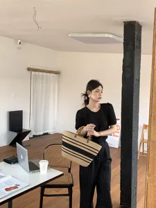 Vista dettagliata della borsa tote in paglia intrecciata con strisce nere e manici in bambù.