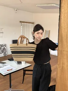 Vista dettagliata della borsa di paglia intrecciata con manici in bambù e righe chic.