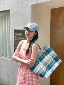 Detailopname van de blauw-witte geweven tote bag, zomerse casual mand handtassenstijl.
