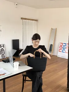 Vista dettagliata di una borsa intrecciata nera con manici in bambù in un soggiorno moderno.