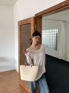 Primo piano sul dettaglio della borsa inpaglia estiva con manico di bambù nella scena.