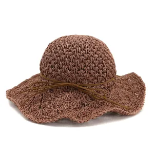 Detailed view of the brown straw hat, showing delicate woven texture and stylish bow tie string.