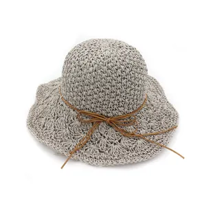 Detail view of the hand-crocheted straw hat with delicate hollow-out pattern and brown cord bow.