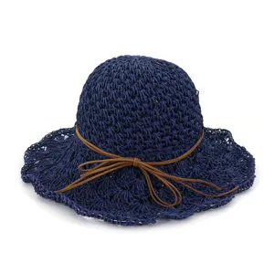 Close-up detail of navy blue crochet straw hat featuring brown suede bow decoration.