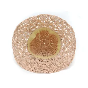 Detail view of a beige handmade crochet straw hat, showing interior texture and mesh design.