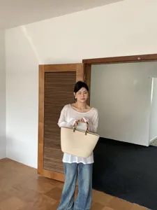 Dettaglio di una borsa tote beige in corda di cotone con eleganti manici in bambu estivi.