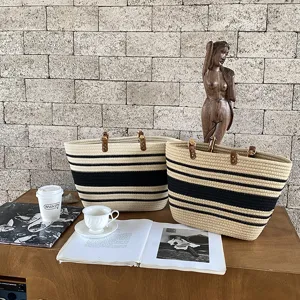 Dettaglio di borsa shopper in corda di cotone intrecciata con motivo a righe e manici in pelle.