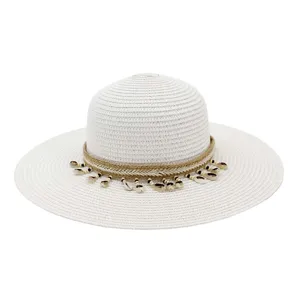 Gros plan détail du chapeau de paille à large bord pour femmes avec corde tressée et coquillages.