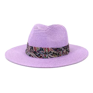 Close up detail of purple straw fedora hat featuring colorful paisley ribbon band decor.