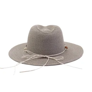 Detail view of the elegant grey straw sun hat featuring a delicate tied cord and wooden bead accents.