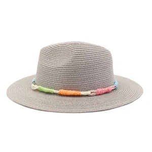 Close-up detail view of the woven straw texture and colorful braided decorative band on the sun hat.