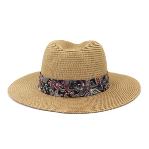 Detailed view of summer straw sun hat featuring colorful paisley ribbon band for beach travel.