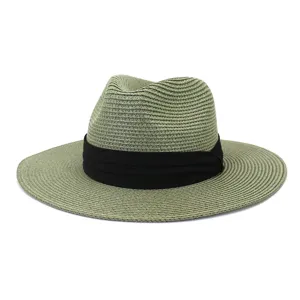 Detail shot of green straw fedora sun hat with black band for summer beach and outdoor use.