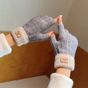 Detail view of winter women's half finger knit gloves in grey and beige with leather tag.