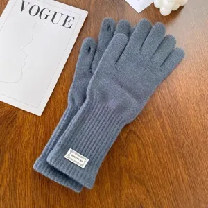 Close-up detail of grey winter knitted touchscreen gloves laid flat with cozy background.