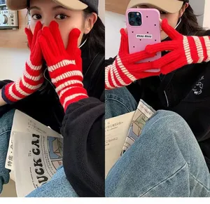 Close-up detail of cozy red and white striped knit fingerless gloves worn by model in winter.