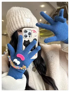 Cute funny blue knit gloves with plush eyes and colorful braids for winter warmth detail.