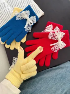 Detailed shot of women's warm knit gloves with delicate lace bows and touch screen design.