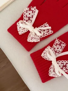 Close-up of red knit gloves featuring sweet white lace bow details for winter warmth and cozy style.