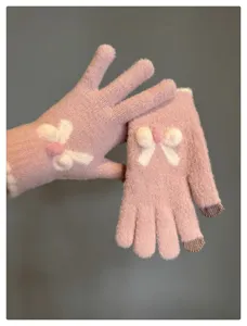 Close-up detail of cute pink knitted touchscreen gloves with lovely bowknot design for winter.
