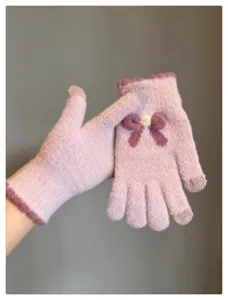 Detailed view of cute winter knitted gloves for women with touchscreen fingers and bow design.