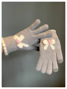 Detail view of women winter touchscreen knitted gloves featuring cute plush bow and warm fabric.