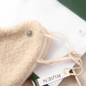 Detalle de la mascarilla facial de invierno en suave felpa beige con cristal brillante.