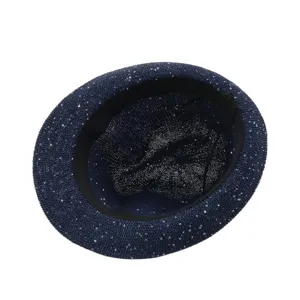 Close-up detail of dark blue sparkling fedora straw hat showing the inner weave texture