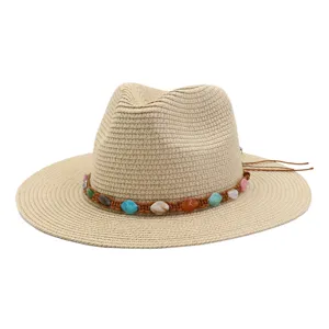 Vue détaillée d'un chapeau de paille d'été à large bord avec bande de perles colorées.
