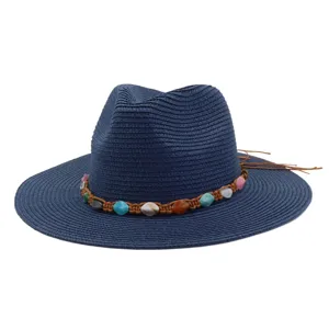 Vue détaillée du chapeau de paille bleu marine avec cordon tressé marron et pierres colorées.
