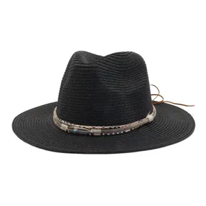 Zwarte strohoed met een gevlochten boho band, veren bedel en lederen strikdetail.