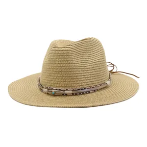 Gedetailleerde opname van zomerstrohoed, brede rand met decoratieve band en turquoise bedel.