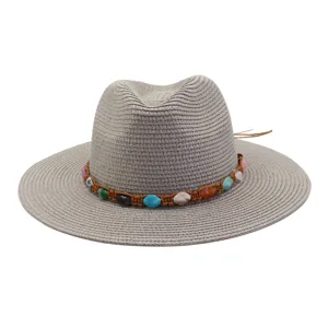Vue détaillée d'un chapeau de paille tissé gris avec une bande tressée de pierres précieuses.