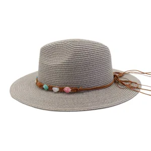 Vue détaillée du chapeau de paille gris avec bande tressée de perles de pierre et nœud latéral.