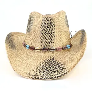 Vue détaillée du chapeau de cowboy en paille avec une bande de coquillages décorative.