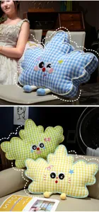 Vista detallada de adorables cojines de peluche a cuadros con rostros bordados en un hogar acogedor.