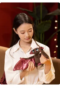 Close-up detail of quirky vampire bat plush toy with pink wings held by model.