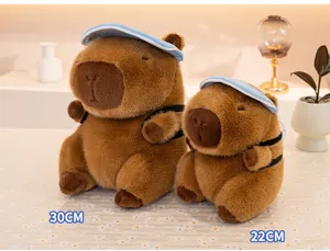 Vue détaillée de peluche capybara mignonne, poupée animal en peluche douce avec casquette bleue.