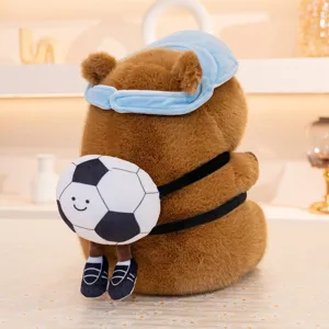 Jolie peluche capybara mignonne avec sac à dos ballon de football et masque de sommeil bleu.
