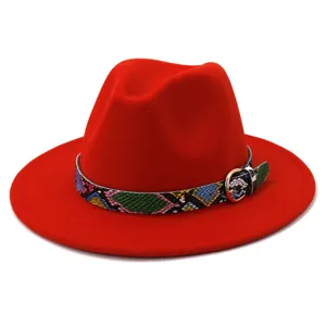 Detalle de sombrero fedora rojo con cinturón de serpiente colorida y hebilla metal.
