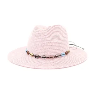 Detail chapeau de plage en paille rose, bande de perles coquillage, protection solaire ete.